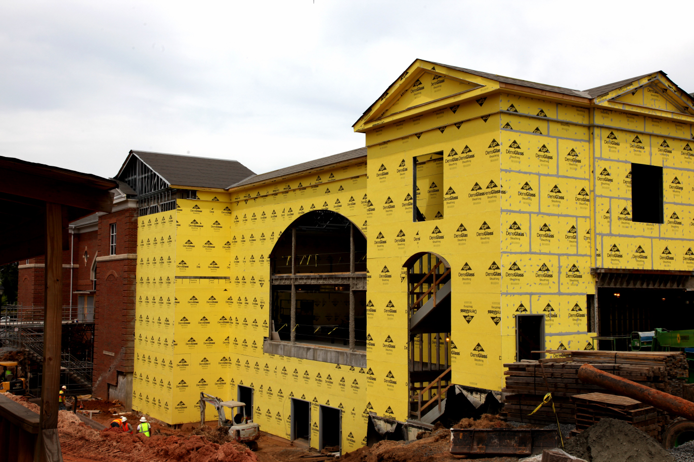 An image showcasing DensGlass Sheathing installed on the exterior of a multi-family building under construction. The sheathing features the distinct yellow fiberglass mat-faced panels, designed to provide moisture resistance and enhanced durability before final cladding installation.
